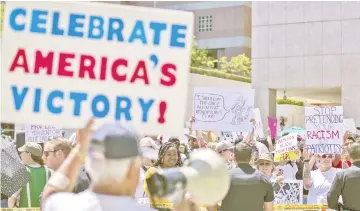  ?? — AFP photo ?? A pro-Trump counter demonstrat­or holds a sign toward protesters decrying Trump administra­tion immigratio­n and refugee policies in Los Angeles.