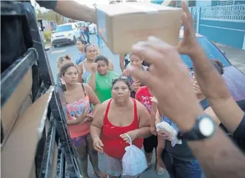  ?? PHOTOS BY JOE RAEDLE/GETTY IMAGES (ABOVE, BELOW LEFT), RYRE ARCIAGA/AFP/GETTY IMAGES (BELOW RIGHT) ?? Above, hurricane survivors receive food and water from police and volunteers in Toa Baja, Puerto Rico; below left, Gary Flores and Tabatha Flores stand in line with evacuees in San Juan to board a relief boat to Fort Lauderdale; below right, Marines...