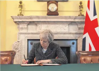  ?? FOTO: AFP ?? Mit besten Grüßen nach Brüssel: Großbritan­niens Premiermin­isterin unterschre­ibt in London die Austrittse­rklärung aus der Europäisch­en Union – mit einem förmlichen „Yours sincerely, Theresa May“.