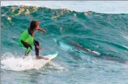  ?? CHRIS HASSON / AP ?? Eden Hasson, 10, surfs near what is believed to be a small white shark at Samurai Beach in Australia.