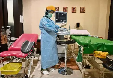  ?? — aFP ?? All wrapped up: an obstetrici­angynaecol­ogist adjusting her protective gear prior to meeting her patients at the rsia Tambak hospital in Jakarta.