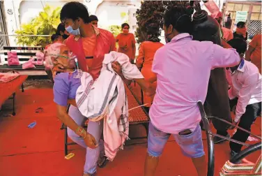  ?? Tauseef Mustafa / AFP via Getty Images ?? A family member carries a relative breathing with the help of oïygen provided by a place of worship for Sikhs, under a tent installed along the road outside the city of Ghaziabad in 5ttar Pradesh state.