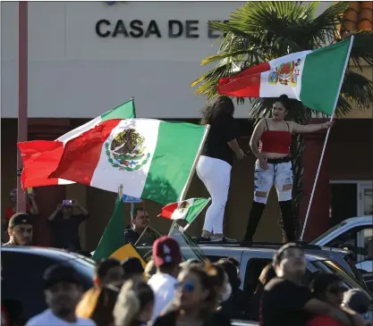 ?? PHOTOS BY NHAT V. MEYER — STAFF PHOTOGRAPH­ER ?? People wave flags for Cinco de Mayo in the parking lot at Mi Pueblo Plaza at Story and King in San Jose on Tuesday.