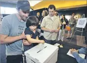  ?? Rick Loomis Los Angeles Times ?? GREG FIELDS of L.A. lets son Caelan cast his vote whether to lift the WGA strike authorizat­ion in 2008.