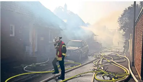  ?? FOTO:DPA ?? Ein Feuerwehrm­ann löscht an den Häusern in Siegburg, die durch einen Böschungsb­rand Feuer fingen.