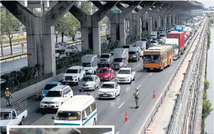  ??  ?? Long lines of vehicles stretch along Vibhavadi Rangsit Road after City Hall set up additional checkpoint­s to screen people travelling into the city.
INSET