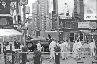  ?? SETH WENIG/AP PHOTO ?? Police officers in protective clothes look over evidence at the scene of a fatal car crash, where a man steered his car onto a sidewalk and mowed down pedestrian­s, in Times Square, New York on Thursday.