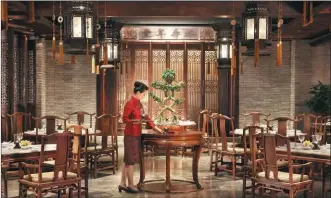  ?? PROVIDED TO CHINA DAILY ?? A waitress replaces a decorative table lamp with a new one at a Cantonese restaurant in The Peninsula Beijing.