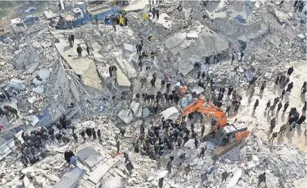  ?? OMAR HAJ KADOUR/ AFP VIA GETTY IMAGES ?? Residents and workers with heavy equipment search flattened buildings for survivors in Besnia, Syria, near the Turkish border Monday after a 7.8 magnitude earthquake struck at 4: 17 a. m. local time.