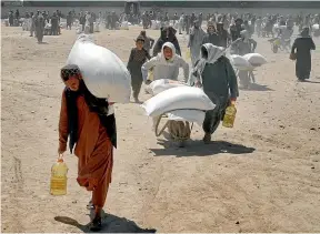  ?? AP ?? Afghans receive food from a Chinese aid group for the Muslim holy month of Ramadan, in Kabul. A new UN report says food insecurity is poised to hit ‘‘appalling’’ new levels worldwide as the Ukraine war affects global food production.