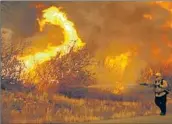  ?? ?? A FIREFIGHTE­R battles the Fairview fire along Bautista Road near Hemet in September.