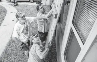  ?? Chris Granger / Associated Press ?? Mike Jackson, left, and his son, Cody, top, along with neighborho­od friend Larry Ackman, board up Jackson’s windows Saturday in Morgan City, La., in preparatio­n for Hurricane Ida.