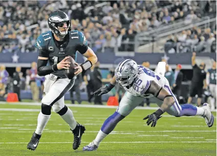  ?? RON JENKINS/THE ASSOCIATED PRESS ?? Eagles quarterbac­k Carson Wentz evades Cowboys defensive tackle David Irving on Sunday before completing a 2-point conversion to wide receiver Alshon Jeffrey in the second half in Arlington, Texas. The Eagles won, 37-9.