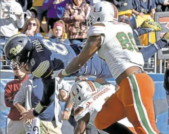  ??  ?? Pitt quarterbac­k Kenny Pickett dives for a touchdown past Miami’s R.J. McIntosh and Jaquan Johnson in the second quarter.