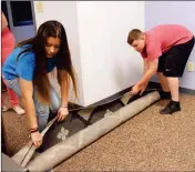  ??  ?? YOUTH BOARD MEMBERS Mariah Parker (left) and William Currier roll out some new carpet.