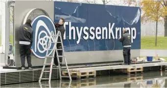 ?? — Reuters ?? Workers carry a cover with the logo of ThyssenKru­pp AG at the company's headquarte­rs in Essen, Germany.
