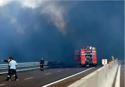  ?? AFP ?? Firefighte­rs work at the scene where a tanker truck exploded on a motorway just outside Bologna, northern Italy. —