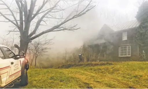  ?? BY JOHN MCCASLIN ?? The first firefighte­r on the scene of a fatal fire on Keyser Run Road enters the burning home.