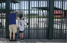  ?? SUE OGROCKI ?? FILE - Cubs fans take photos through the locked gates at Sloan Park, the spring training site of the Chicago Cubs, in Mesa, Ariz., in this Friday, March 13, 2020, file photo.