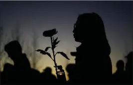  ?? ASHLEY LANDIS — THE ASSOCIATED PRESS ?? A woman holds a candle and a flower during a vigil outside Monterey Park City Hall, blocks from the Star Ballroom Dance Studio, late Tuesday.