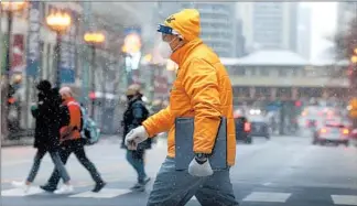  ?? ANTONIO PEREZ/CHICAGO TRIBUNE ?? Pedestrian­s deal with cold temperatur­es and a bit of snow while walking Monday in downtown Chicago.