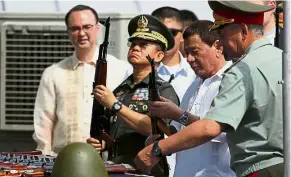  ?? — AFP ?? Getting the big guns: Duterte (in white) inspecting Kalashniko­v rifles during the handover ceremony at the Port of Manila.