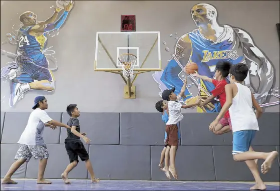  ?? AP ?? Boys play basketball in a newly opened court inspired by NBA legend Kobe Bryant. The House of Kobe was inaugurate­d last Sunday, a day before Bryant’s passing. Fans left flowers and messages on the walls yesterday after learning of the tragedy.