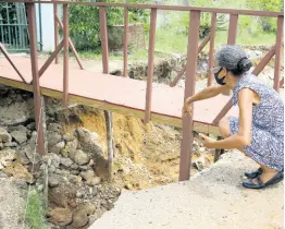  ?? ?? Lorelei Mulgrave points to an area where she attempted to place stones after the soil under the makeshift bridge began to erode.