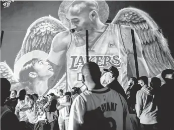  ?? BRANDON BELL/GETTY ?? Lakers fans stand in line to celebrate in front of a mural of Kobe Bryant and his daughter Gianna Bryant on Oct. 11 in Los Angeles. People gathered to celebrate after the Lakers defeated the Heat in Game 6 of the NBA Finals.