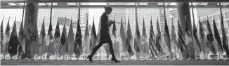  ??  ?? A woman walks past the flags of participan­ts at the UN peacekeepi­ng conference in Vancouver.