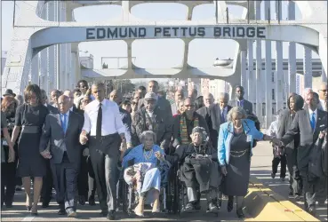 ?? JACQUELYN MARTIN — THE ASSOCIATED PRESS FILE ?? In this March 7, 2015, file photo, singing “We Shall Overcome,” President Barack Obama, third from left, walks holding hands with Amelia Boynton, who was beaten during “Bloody Sunday,” as they and the first family and others including Rep. John Lewis, D-Ga, left of Obama, walk across the Edmund Pettus Bridge March 7, 2015 in Selma, Ala., for the 50th anniversar­y of “Bloody Sunday,” a landmark event of the civil rights movement.