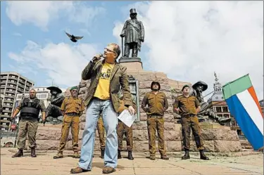  ?? KIM LUDBROOK/EPA ?? An activist for Afrikaner rights, Steve Hofmeyr, gives a speech earlier this year at the statue of Afrikaner hero Paul Kruger in Pretoria, South Africa. Some blacks in the country say the effect of apartheid remains ever present.