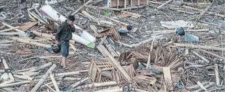  ?? CARL COURT GETTY IMAGES ?? A man covers his nose as he walks through the rubble and debris of a building that was destroyed by a tsunami, on Oct. 1 in Palu, Indonesia.