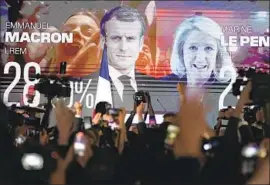  ?? Francois Mori Associated Press ?? FRENCH PRESIDENT Emmanuel Macron and far-right candidate Marine Le Pen are shown on a screen at Le Pen’s election day headquarte­rs in Paris.