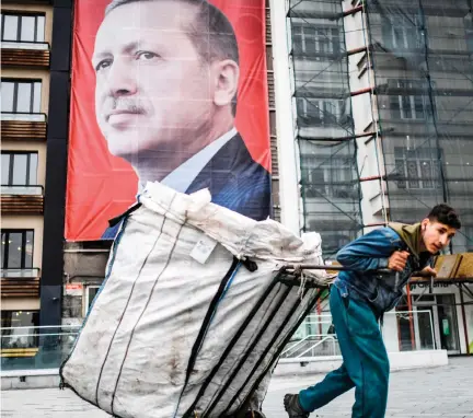  ??  ?? A man pulls a cart in front of a huge portrait of Turkish President Recep Tayyip Erdogan on Taksim Square in Istanbul. (AFP)