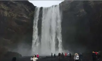  ?? SHEILA NORMAN-CULP — THE ASSOCIATED PRESS ?? Tourists view the Skogafoss waterfall, southwest of the Myrdalsjok­ull ice cap that covers the feared Katla volcano, about 20 miles west of Vik, Iceland.