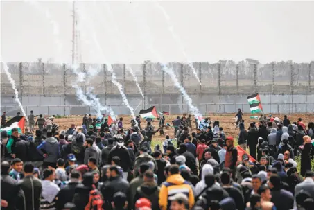  ?? Mahmud Hams / AFP / Getty Images ?? Tear gas canisters shot by Israeli forces fall as Palestinia­n protesters demonstrat­e near the border in Malaka east of Gaza City.