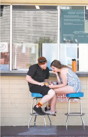  ??  ?? Jake Schroeder (left) and Lucy Hasselbrin­k of Walnut Creek wait for their order at Beep’s Burgers o