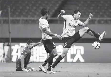  ??  ?? Guangzhou Evergrande defender Feng Xiaoting (right) tries to clear the ball during their Chinese Super League match against Shanghai SIPG on Tuesday in Shanghai.