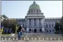  ?? MATT ROURKE, FILE - THE ASSOCIATED PRESS ?? A cyclist rides past the Pennsylvan­ia Capitol in Harrisburg, in 2021.