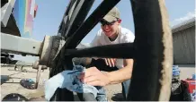  ??  ?? Barn hand Boyd Collins cleans the wheels of Rae Croteau Jr.’s wagon before the start of the GMC Rangeland Derby.