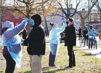  ?? MATT SLOCUM AP ?? Nurses administer COVID-19 tests in Philadelph­ia on Thursday. President Donald Trump on Friday signed a spending bill to avert a government shutdown and secure more time to negotiate a pandemic relief package.