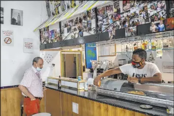  ?? Bernat Armangue The Associated Press ?? A bar owner disinfects the area used Wednesday by a customer in Madrid, a city which accounted last week for one-third of Spain’s new coronaviru­s infections.