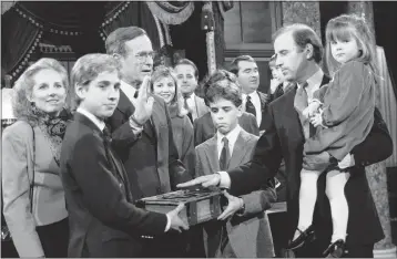  ?? LANA HARRIS — THE ASSOCIATED PRESS FILE ?? Sen. Joe Biden, D-Del., holds his daughter Ashley while taking a mock oath of office from Vice President George Bush during a ceremony on Capitol Hill in Washington. Biden’s sons Beau and Hunter hold the Bible during the ceremony in January 1985.