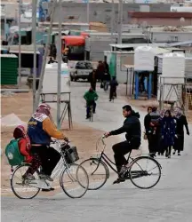  ?? Fotos Muhammad Amed - 30.nov.2016/Reuters ?? Sírios de bicicleta na rua principal do campo de Zaatari