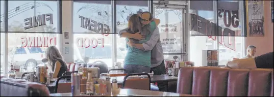  ?? Netflix ?? Deanna Thompson of Las Vegas and John Green of California share a hug at a diner. They were both part of a Facebook group “Find the kitten vacuumer… for great justice,” that worked to find a killer.