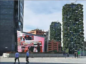  ?? MIGUEL MEDINA / AGENCE FRANCE-PRESSE ?? People walk in front of the architectu­ral complex designed by Studio Boeri, the “Bosco Verticale” (Vertical Forest), in the Porta Nuova area of Milan.