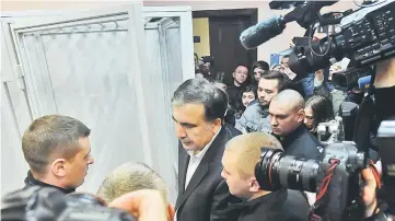  ??  ?? Saakashvil­i (centre) surrounded by the media as he exits a glass cage, within his hearing at the courthouse of Kiev. — AFP photo