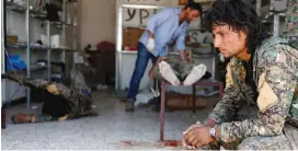  ?? (Goran Tomasevic/Reuters) ?? A SYRIAN DEMOCRATIC FORCES fighter waits in Raqqa while medics treat his comrades, in the spring.