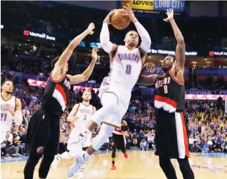  ??  ?? Oklahoma City Thunder guard Russell Westbrook (0) goes up for a shot between Portland Trail Blazers guard C.J McCollum, left, and forward Al-Farouq Aminu (8) in the fourth quarter of an NBA basketball game in Oklahoma City on Tuesday night. (AP)